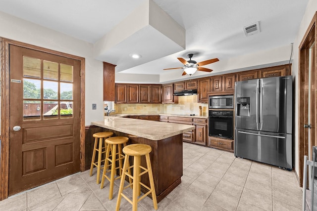 204 Glenwick Pl, Allen, TX 75013 - kitchen with black appliances, under cabinet range hood, light tile patterned floors, a peninsula, and light countertops