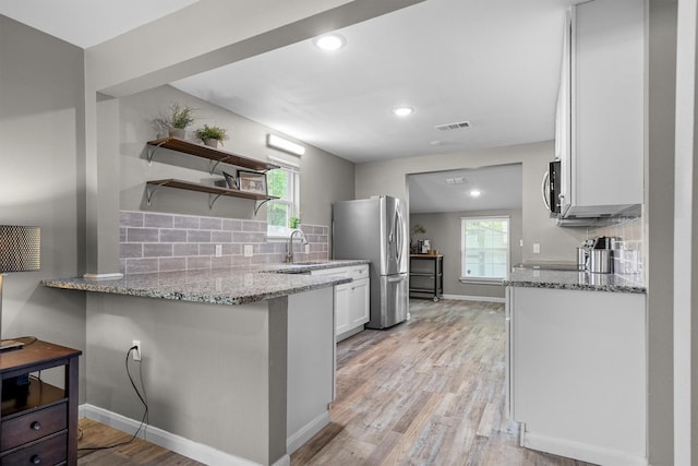 406 N Ruddell St, Denton, TX 76209 - kitchen with appliances with stainless steel finishes, light stone counters, tasteful backsplash, white cabinets, and light wood finished floors