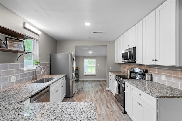 406 N Ruddell St, Denton, TX 76209 - kitchen with stainless steel appliances, a sink, open shelves, backsplash, and light wood finished floors