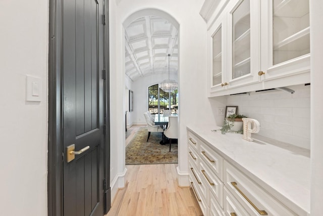 2 Terrabella Ln, Heath, TX 75032 - bar with vaulted ceiling, light wood finished floors, arched walkways, decorative backsplash, and baseboards