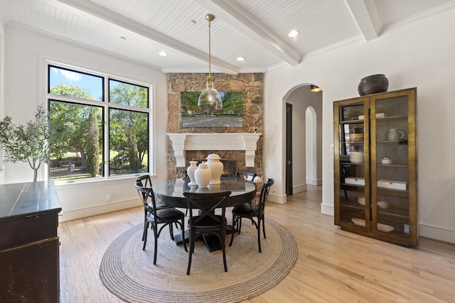 2 Terrabella Ln, Heath, TX 75032 - dining area with arched walkways, light wood-style floors, beamed ceiling, a stone fireplace, and baseboards