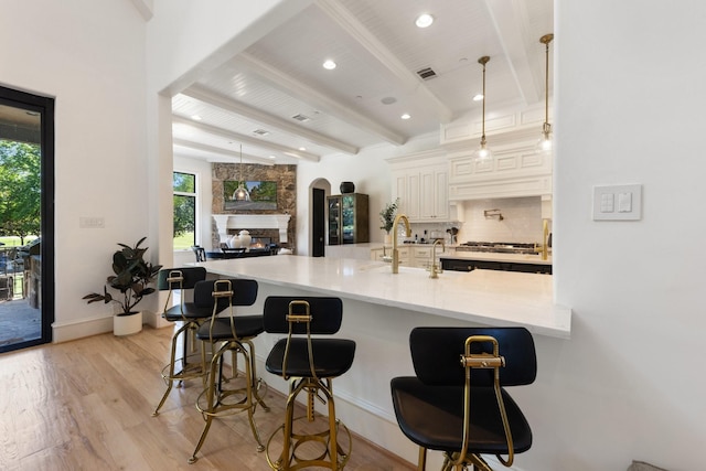 2 Terrabella Ln, Heath, TX 75032 - kitchen featuring beam ceiling, plenty of natural light, light wood-type flooring, decorative backsplash, and a breakfast bar