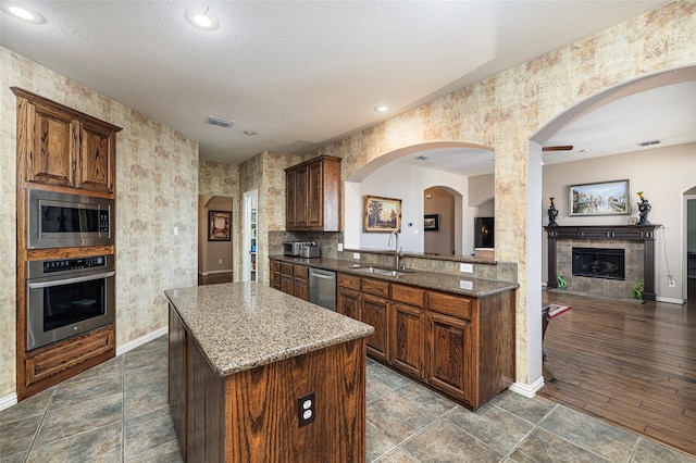 437 Fox Trl, Allen, TX 75002 - kitchen featuring stainless steel appliances, a sink, baseboards, a center island, and dark stone counters