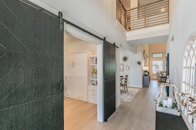 14709 Storyteller Ln, Fort Worth, TX 76052 - corridor with a barn door, a high ceiling, light wood-style floors, and baseboards