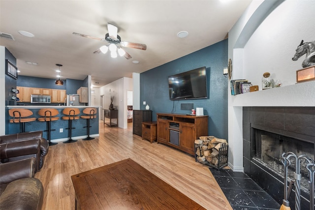 1053 Pullman Dr, Saginaw, TX 76131 - living area with ceiling fan, wood finished floors, a fireplace, a textured wall, and baseboards
