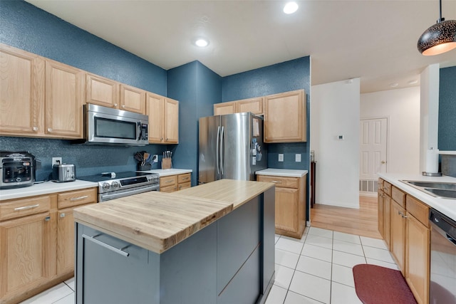 1053 Pullman Dr, Saginaw, TX 76131 - kitchen featuring appliances with stainless steel finishes, butcher block countertops, light brown cabinets, light tile patterned floors, and recessed lighting