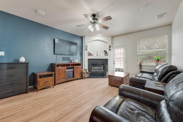 1053 Pullman Dr, Saginaw, TX 76131 - living area featuring ceiling fan, a textured wall, a fireplace with flush hearth, and light wood-style floors
