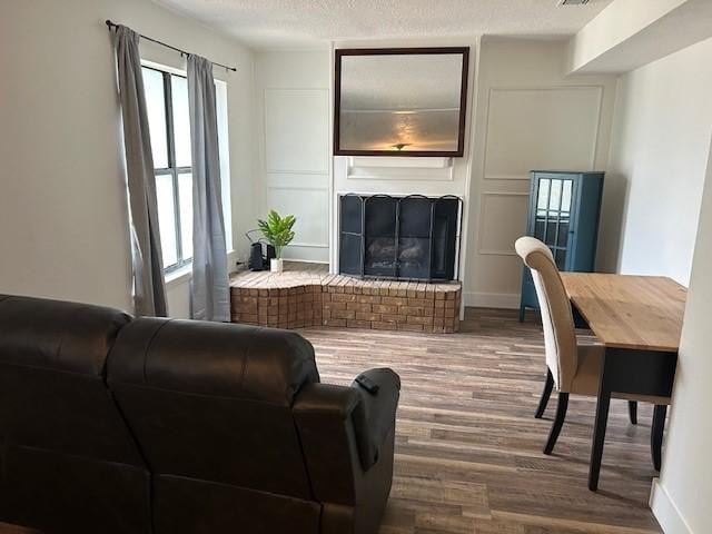 3624 Aurora St, Haltom City, TX 76117 - living area featuring wood finished floors, a brick fireplace, and a textured ceiling