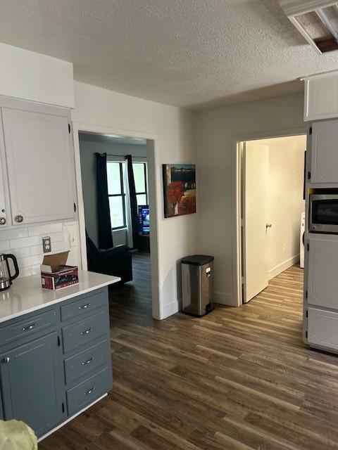 3624 Aurora St, Haltom City, TX 76117 - kitchen featuring gray cabinetry, dark wood finished floors, backsplash, stainless steel microwave, and a textured ceiling