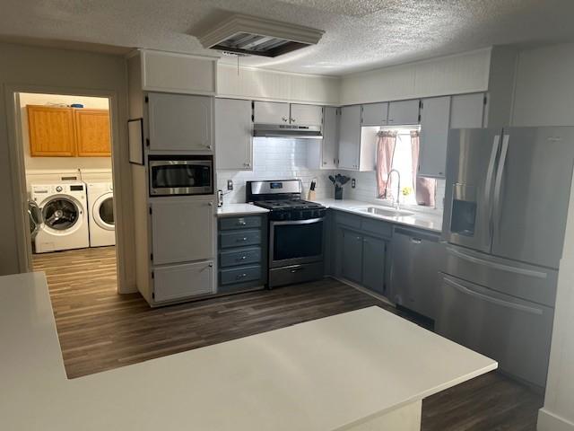 3624 Aurora St, Haltom City, TX 76117 - kitchen with appliances with stainless steel finishes, a sink, washer and dryer, gray cabinetry, and a textured ceiling