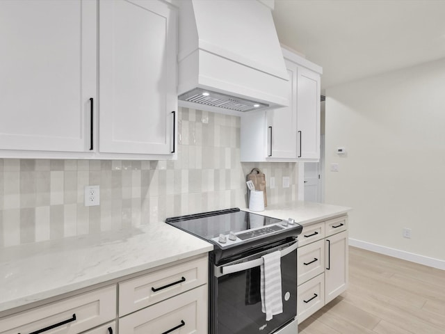2207 Irion Ave, Fort Worth, TX 76106 - kitchen with stainless steel electric range oven, custom exhaust hood, tasteful backsplash, white cabinets, and light stone countertops