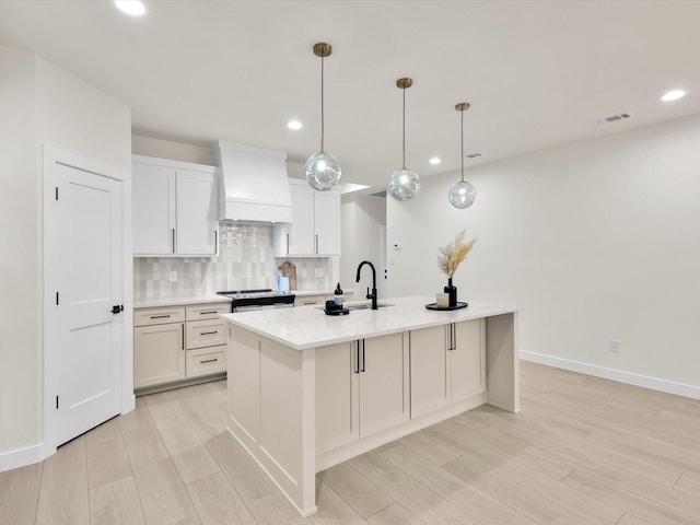 2207 Irion Ave, Fort Worth, TX 76106 - kitchen featuring premium range hood, a sink, recessed lighting, light wood finished floors, and decorative backsplash