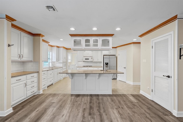 120 Wooded Crest Dr, Woodway, TX 76712 - kitchen with white appliances, ornamental molding, a sink, a kitchen breakfast bar, and glass insert cabinets