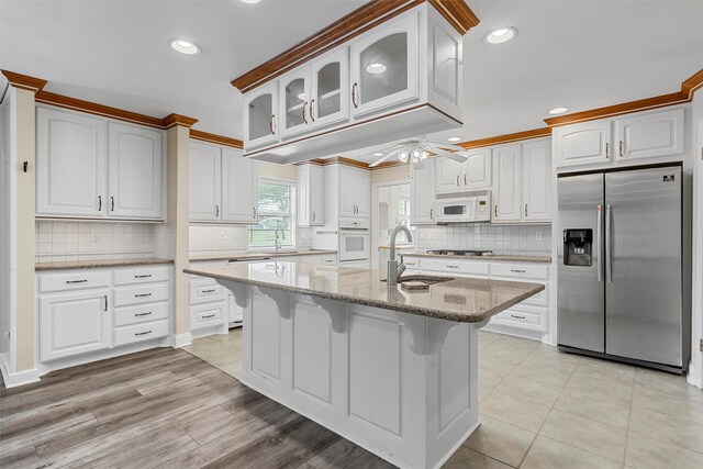 120 Wooded Crest Dr, Woodway, TX 76712 - kitchen featuring stainless steel appliances, a sink, light stone counters, decorative backsplash, and ceiling fan
