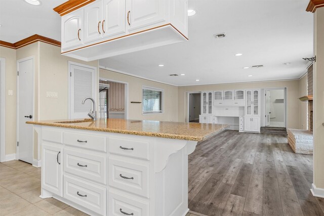 120 Wooded Crest Dr, Woodway, TX 76712 - kitchen with a sink, ornamental molding, light stone countertops, a kitchen island with sink, and white cabinets