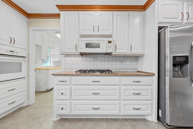 120 Wooded Crest Dr, Woodway, TX 76712 - kitchen with appliances with stainless steel finishes, white cabinetry, light stone counters, light tile patterned floors, and tasteful backsplash