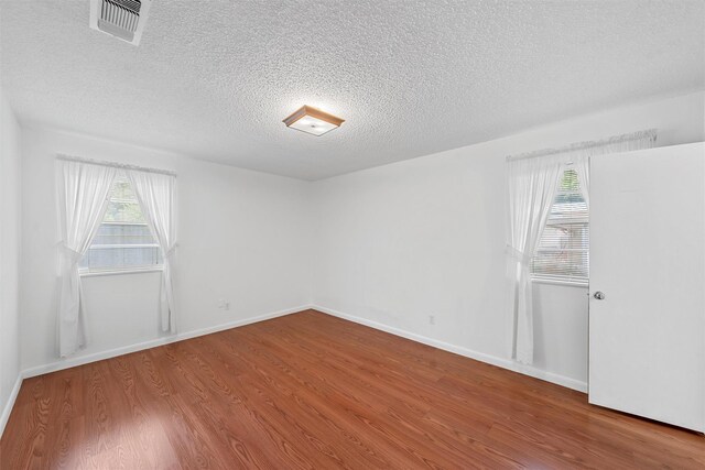 120 Wooded Crest Dr, Woodway, TX 76712 - empty room with wood finished floors, plenty of natural light, a textured ceiling, and baseboards