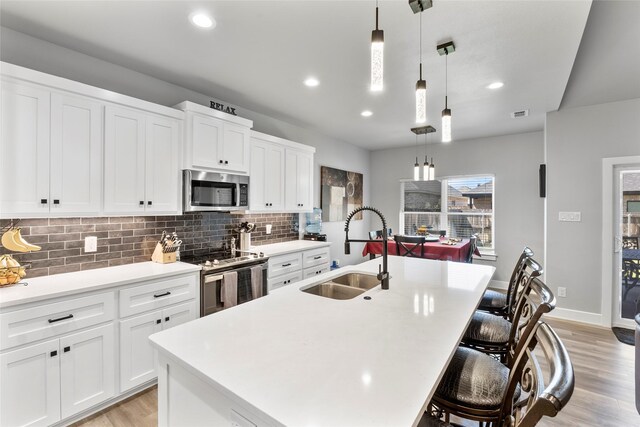 4518 Velta Ln, Abilene, TX 79606 - kitchen featuring stainless steel appliances, a sink, light wood finished floors, tasteful backsplash, and a kitchen island with sink
