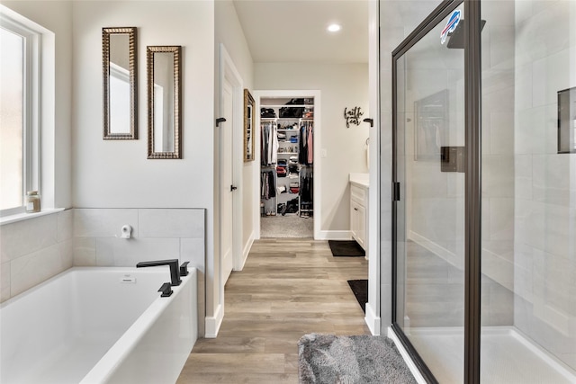 4518 Velta Ln, Abilene, TX 79606 - bathroom with a walk in closet, a stall shower, a garden tub, vanity, and wood finished floors