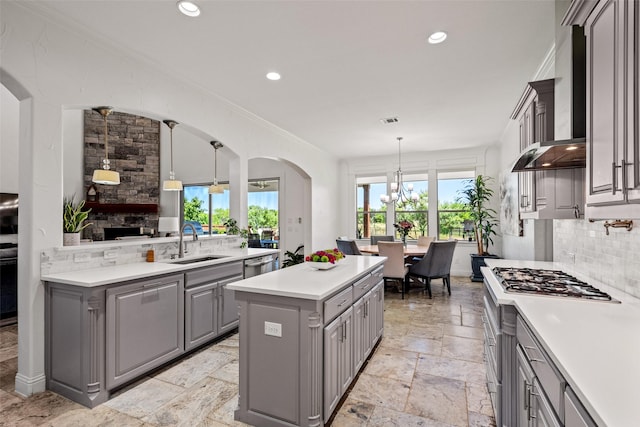 7305 Kingsbarns, The Colony, TX 75056 - kitchen featuring gray cabinets, a sink, wall chimney range hood, appliances with stainless steel finishes, and tasteful backsplash