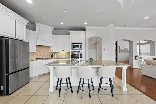 4219 Bal Harbour Ln, Frisco, TX 75033 - kitchen featuring appliances with stainless steel finishes, arched walkways, custom range hood, crown molding, and a sink