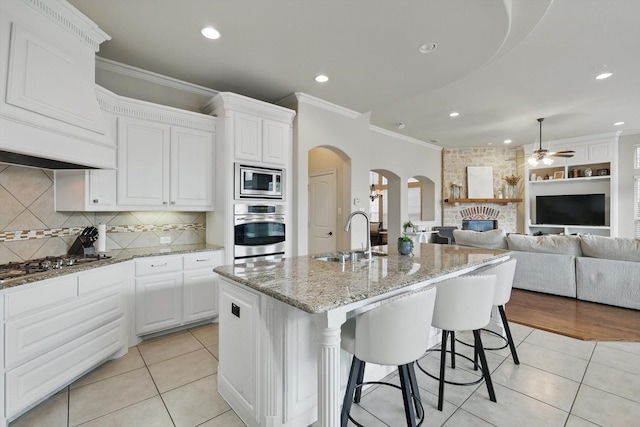 4219 Bal Harbour Ln, Frisco, TX 75033 - kitchen with appliances with stainless steel finishes, a sink, arched walkways, ceiling fan, and a fireplace