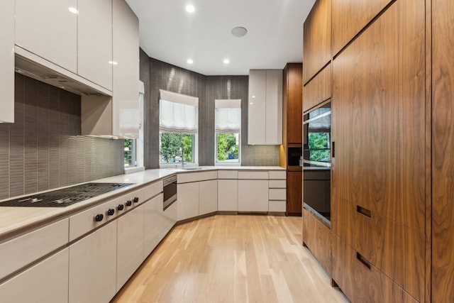 3645 Reagan St, Dallas, TX 75219 - kitchen featuring light wood finished floors, light countertops, modern cabinets, decorative backsplash, and recessed lighting