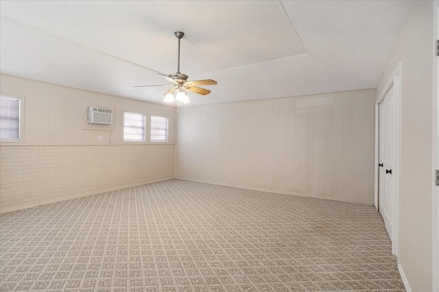 131 S Imperial Dr, Denison, TX 75020 - spare room featuring a ceiling fan, a wall unit AC, brick wall, and carpet flooring