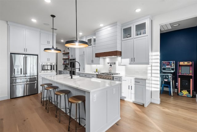 1907 Cedar Bluff Pkwy, Mansfield, TX 76063 - kitchen with appliances with stainless steel finishes, light wood-style flooring, a breakfast bar, a center island with sink, and recessed lighting