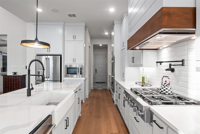 1907 Cedar Bluff Pkwy, Mansfield, TX 76063 - kitchen with premium range hood, appliances with stainless steel finishes, wood finished floors, white cabinetry, and recessed lighting
