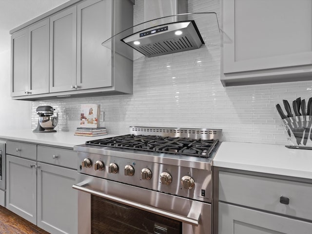 7724 Meadowhaven Dr, Dallas, TX 75254 - kitchen with high end stainless steel range, gray cabinetry, wall chimney range hood, decorative backsplash, and light countertops