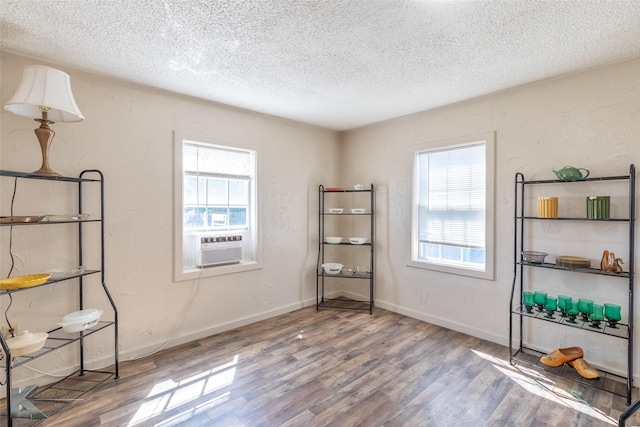 240 5th St, Hawley, TX 79525 - empty room featuring a textured ceiling, wood finished floors, healthy amount of natural light, and cooling unit