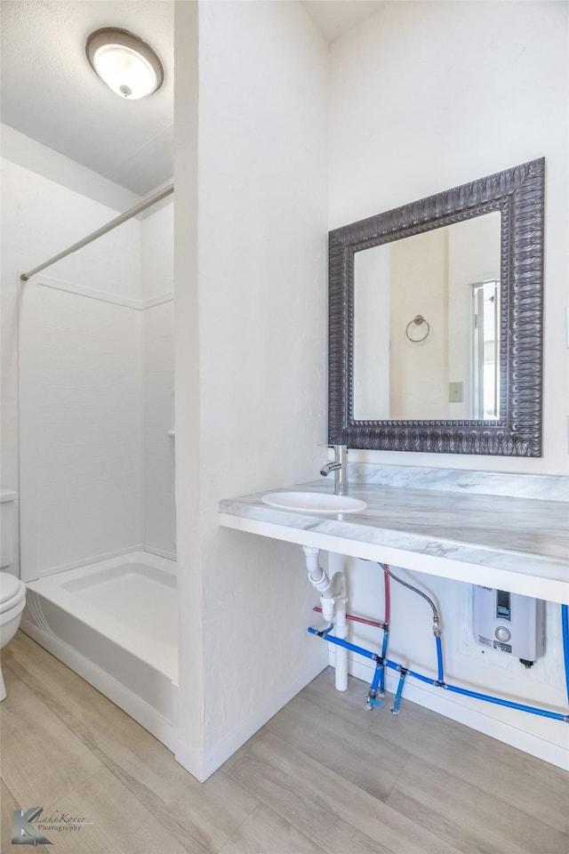 240 5th St, Hawley, TX 79525 - bathroom with toilet, wood finished floors, a shower, and a sink