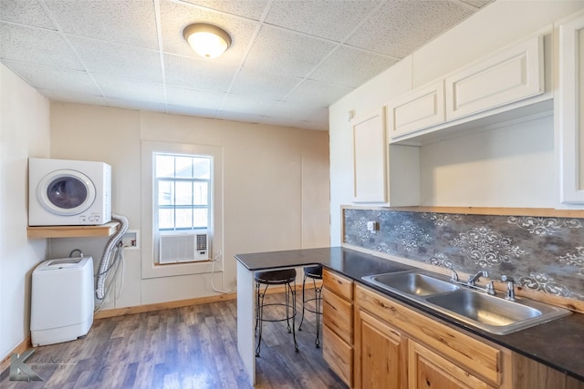 240 5th St, Hawley, TX 79525 - kitchen featuring stacked washing machine and dryer, a sink, dark countertops, dark wood-type flooring, and decorative backsplash