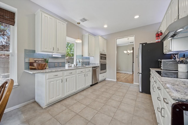8408 Island Ct, Fort Worth, TX 76137 - kitchen featuring appliances with stainless steel finishes, decorative backsplash, a chandelier, under cabinet range hood, and pendant lighting