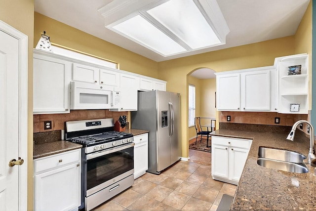 4533 Crooked Ridge Dr, The Colony, TX 75056 - kitchen featuring stainless steel appliances, a sink, arched walkways, open shelves, and white cabinetry