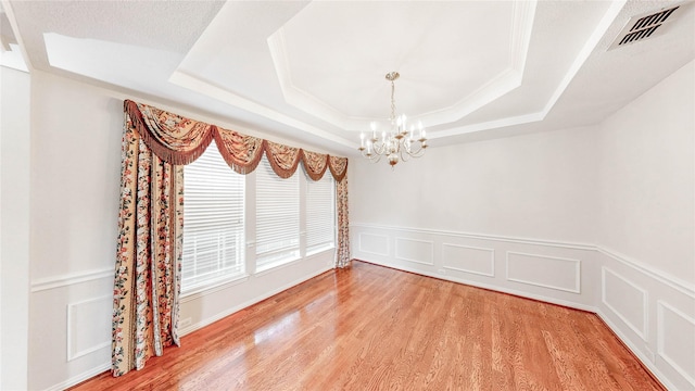 2700 Lake Crest Dr, Flower Mound, TX 75022 - unfurnished room with a chandelier, a raised ceiling, light wood-style flooring, and wainscoting