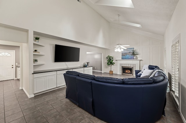 3428 Glade Creek Dr, Hurst, TX 76054 - living room with built in shelves, high vaulted ceiling, a tile fireplace, dark tile patterned floors, and a ceiling fan