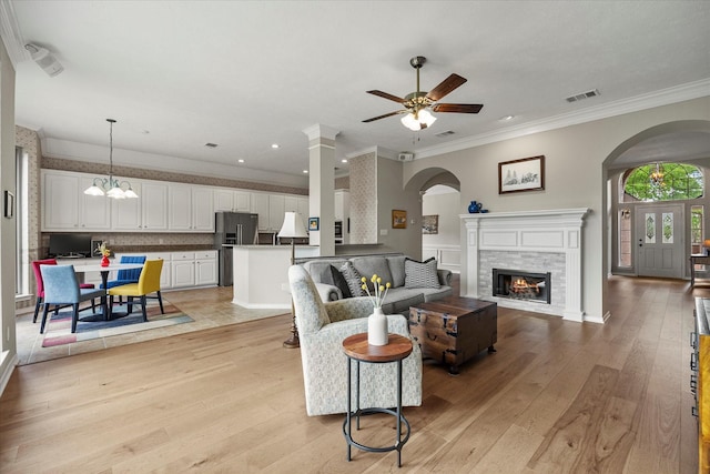 3134 Oak Dr, Rockwall, TX 75032 - living room featuring arched walkways, a ceiling fan, a glass covered fireplace, light wood-style flooring, and crown molding