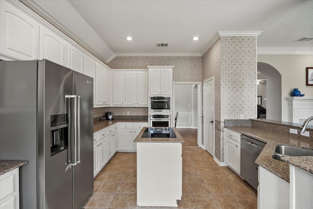 3134 Oak Dr, Rockwall, TX 75032 - kitchen with appliances with stainless steel finishes, crown molding, a sink, dark stone counters, and arched walkways