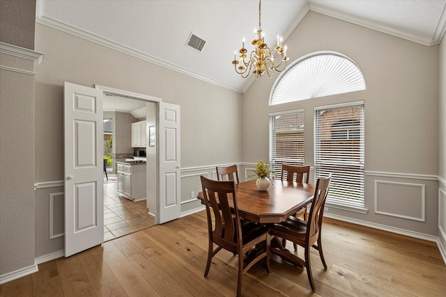 3134 Oak Dr, Rockwall, TX 75032 - dining area featuring vaulted ceiling, ornamental molding, light wood finished floors, and a chandelier