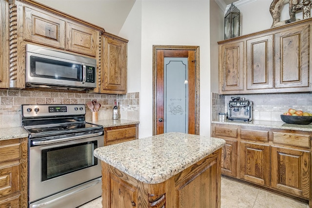 5633 Veal Station Rd, Weatherford, TX 76085 - kitchen with stainless steel appliances, decorative backsplash, light stone countertops, a kitchen island, and crown molding