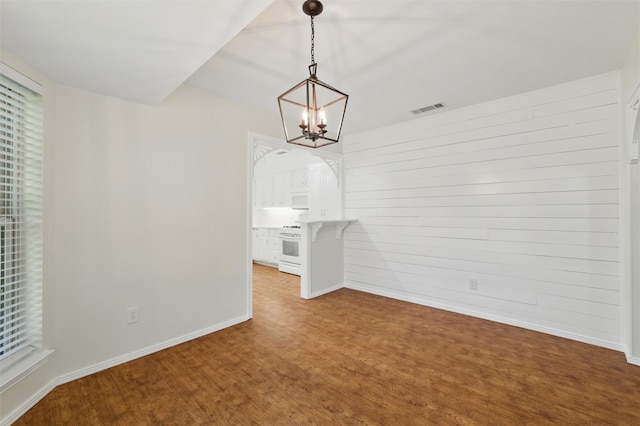 207 Johnston Blvd, Waxahachie, TX 75165 - unfurnished dining area with baseboards, a chandelier, wood finished floors, and wood walls