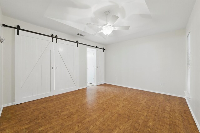 207 Johnston Blvd, Waxahachie, TX 75165 - unfurnished bedroom with a barn door, wood finished floors, baseboards, and ceiling fan