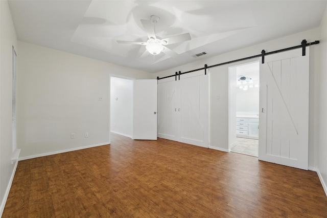 207 Johnston Blvd, Waxahachie, TX 75165 - unfurnished room with a barn door, ceiling fan, wood finished floors, and baseboards