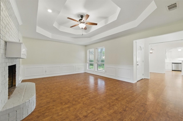 207 Johnston Blvd, Waxahachie, TX 75165 - unfurnished living room with a tray ceiling, ceiling fan, a fireplace, wood finished floors, and a decorative wall