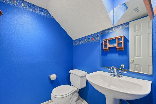 2207 Villanova St, Arlington, TX 76018 - half bathroom featuring lofted ceiling, a sink, baseboards, toilet, and a textured wall