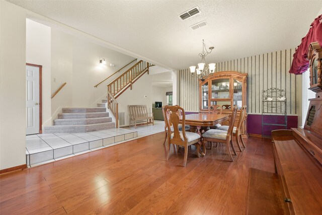 2207 Villanova St, Arlington, TX 76018 - dining area featuring stairway, wood finished floors, a chandelier, a textured ceiling, and baseboards