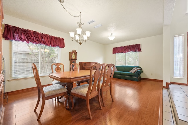 2207 Villanova St, Arlington, TX 76018 - dining area featuring a chandelier, light wood-style flooring, a textured ceiling, and baseboards