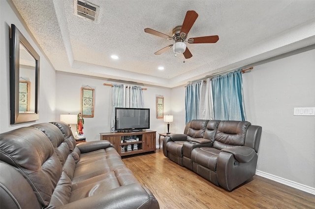 11514 Oakfield Dr, Balch Springs, TX 75180 - living room with a textured ceiling, wood finished floors, ceiling fan, baseboards, and a raised ceiling